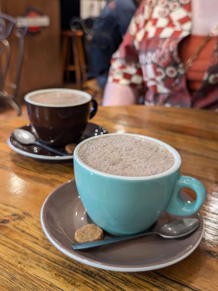 Close up of 2 cups and saucers filled with hot chocolate on a wooden table